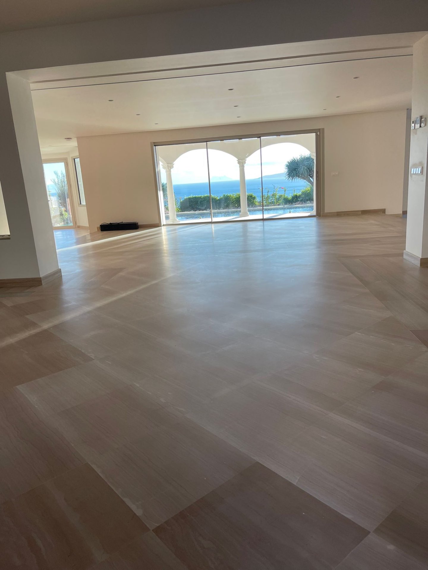 Grand salon avec sol en pierre poli et vue sur la mer